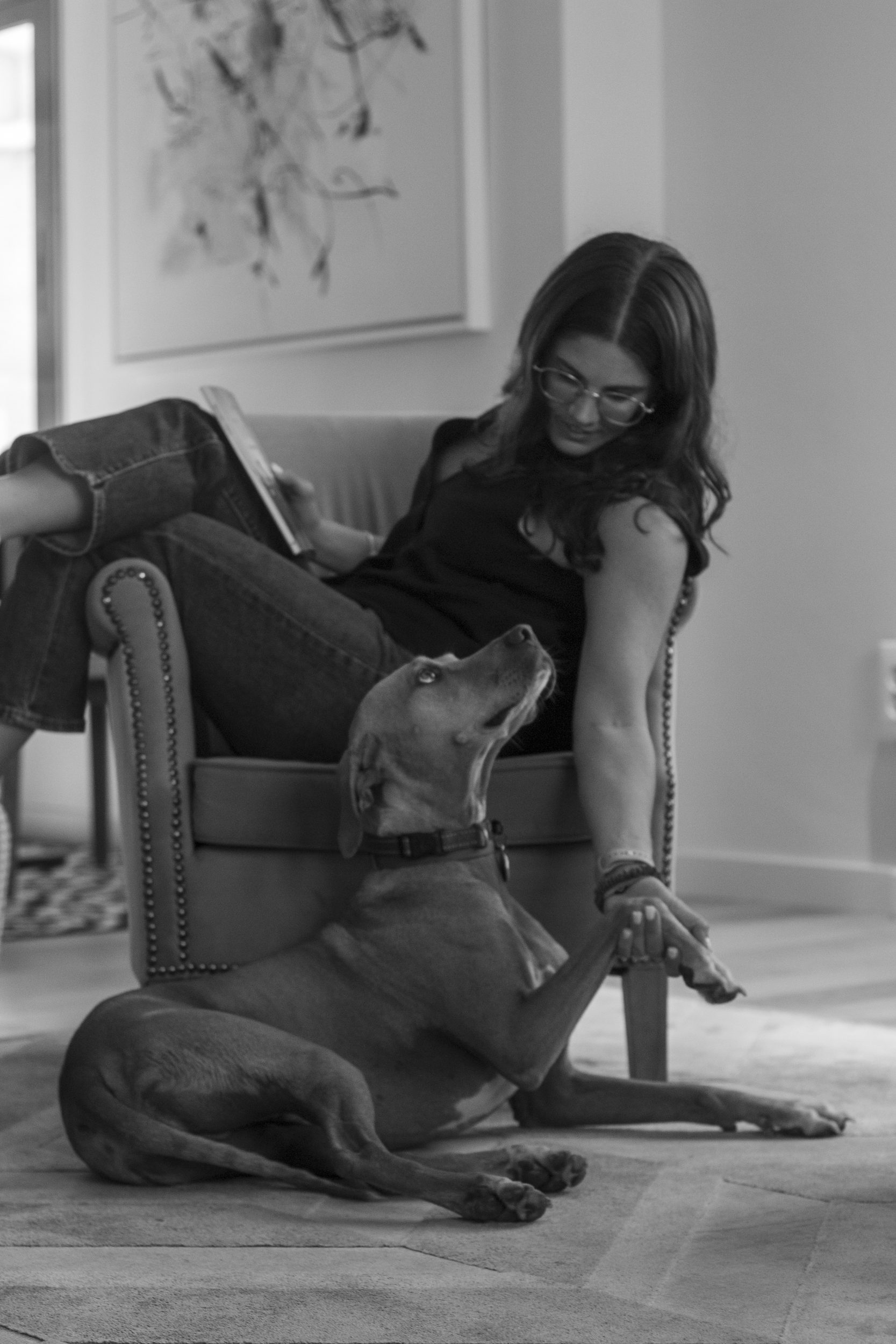 Evelyn P&B lendo na poltrona com o cão