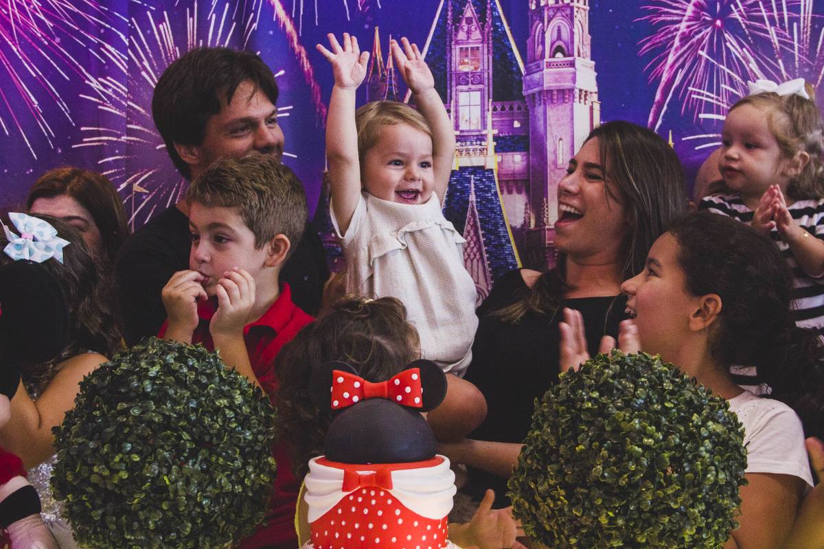 Gabriela raising her arms in front of her Minnie Mouse birthday cake