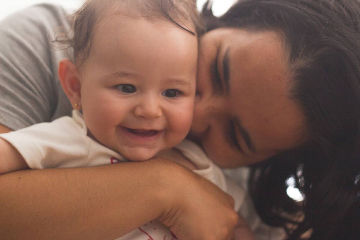 Mariana smiling as her mother nuzzles her cheek