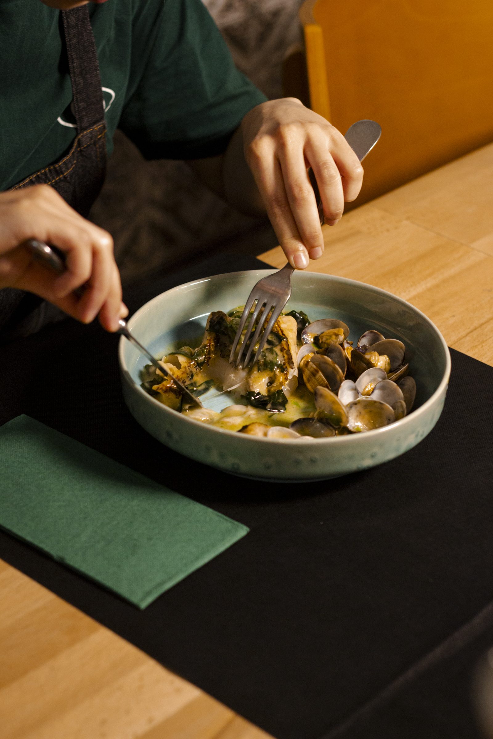Diner cutting into a bowl of clams at Porco Preto